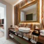 Terme Dobrna - Hotel Švicarija_Badezimmer mit Spiegel und Blick in Zimmer_FC_Terme Dobrna